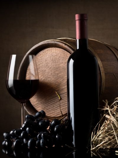 Wine with grape and barrel on brown background